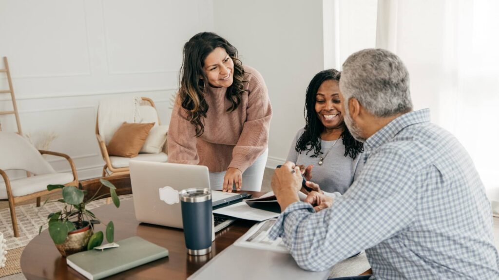 Three people sit at a desk and discuss payroll taxes.