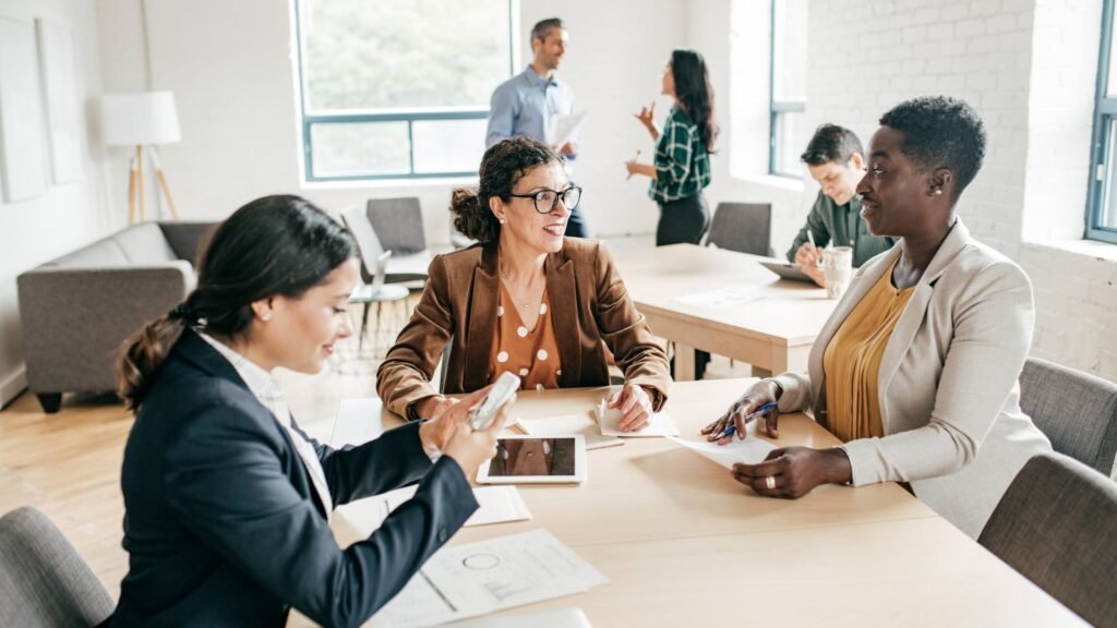 Three people sit around a table and discuss ways to save money.